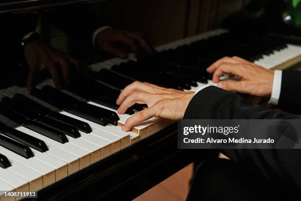 close up shot of the hands of an unrecognizable elegant pianist dressed in a suit playing a grand piano. - classical stockfoto's en -beelden