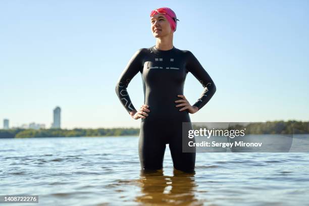 portrait of female swimmer standing into water - lake shore stock pictures, royalty-free photos & images