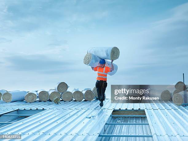 workman carrying rolls of insulation to install into factory roof - lift roof bildbanksfoton och bilder