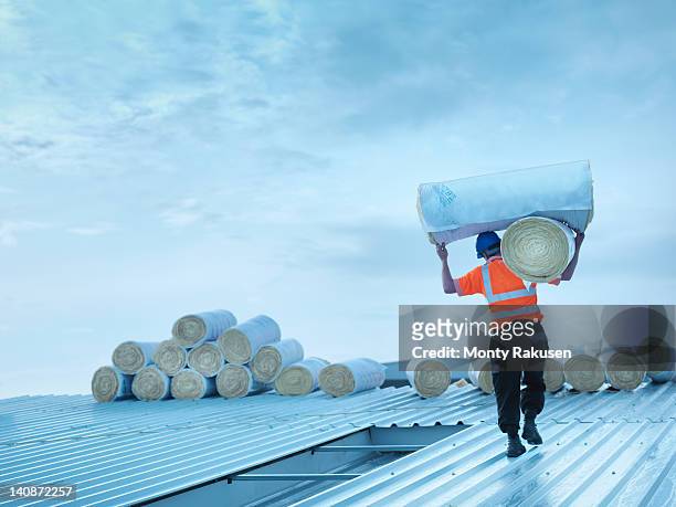 worker carrying insulation on roof - lift roof bildbanksfoton och bilder