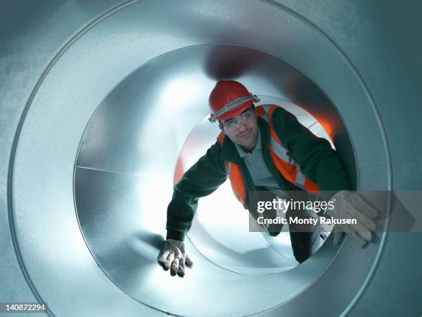 portrait of workman in stainless steel air pipe of building site - crawling stock pictures, royalty-free photos & images