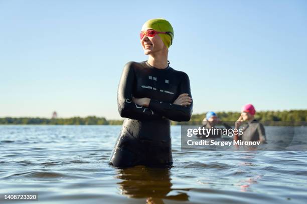 happy swimmer standing into water - wetsuit stock pictures, royalty-free photos & images