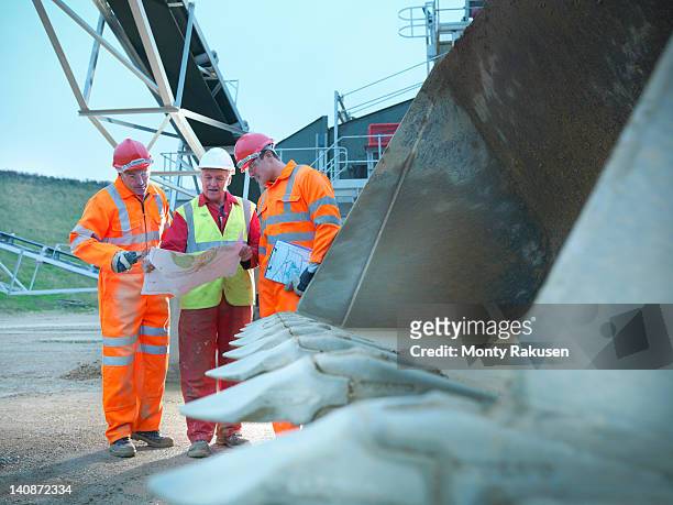 construction workers reading blueprints - bulldozer stock-fotos und bilder