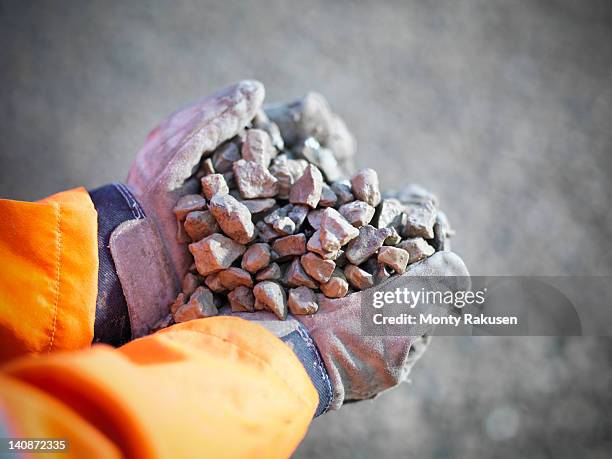 gloved hands holding crushed stones in quarry site - schottergestein stock-fotos und bilder