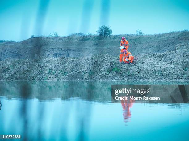 ecologists in reflective clothing inspecting water in quarry site - ecologist stock pictures, royalty-free photos & images