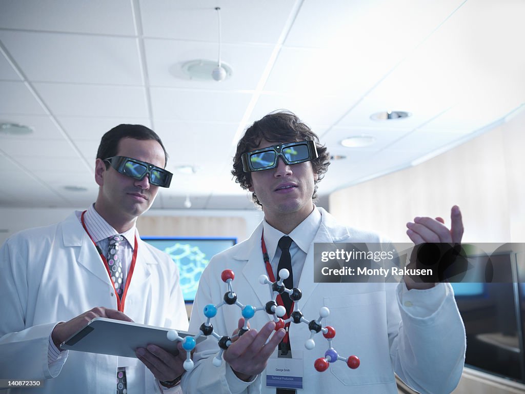 Molecular scientist and apprentice in 3D glasses holding molecular model and digital tablet