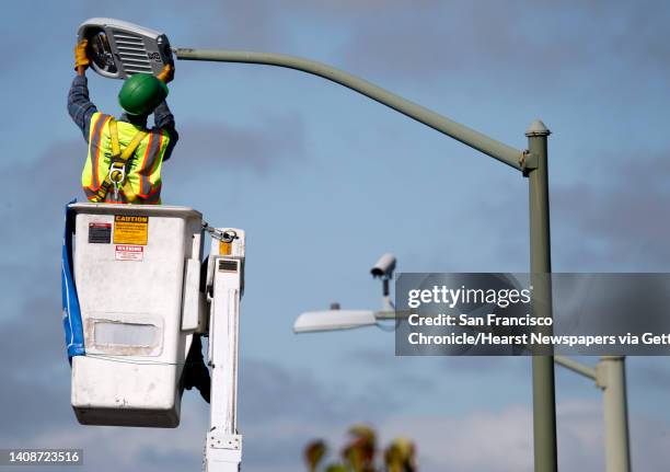 Toan Pham attaches an energy-saving LED fixture to a lamp post at 98th Avenue and MacArthur Boulevard in Oakland, Calif. On Tuesday, June 18, 2013....