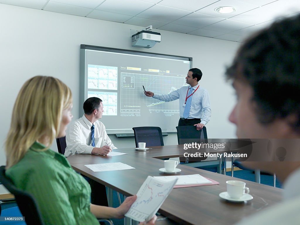 Businessman explaining to colleagues in conference room using smart board