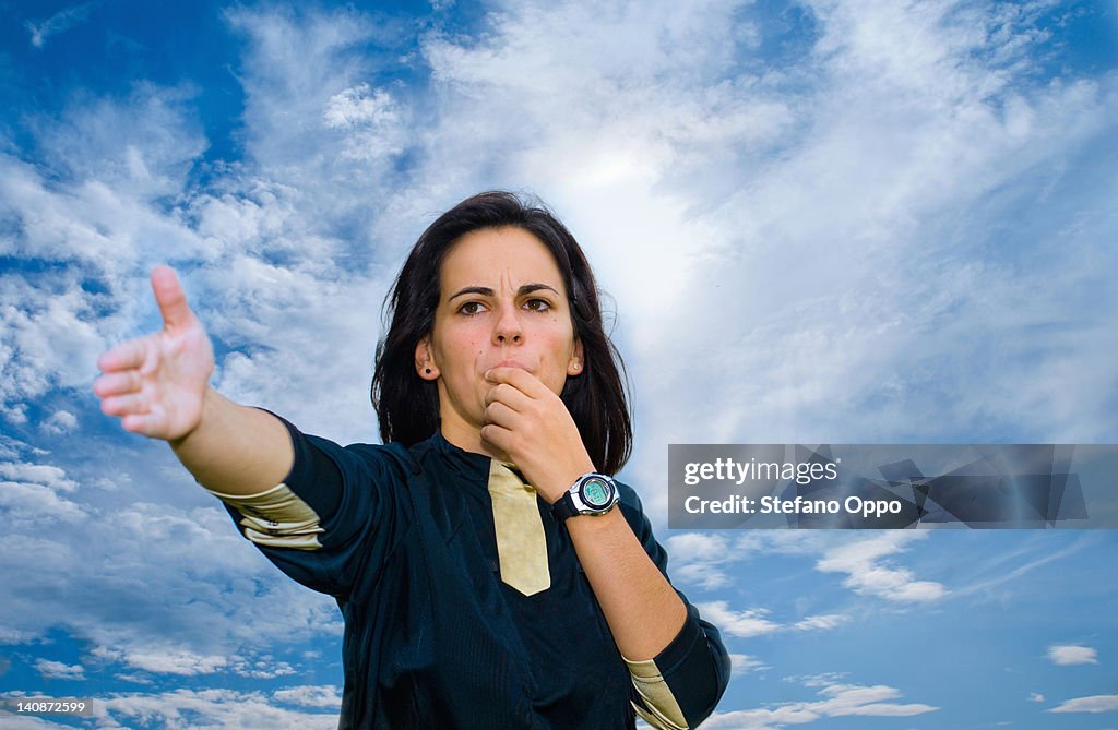 Woman blowing whistle against blue sky