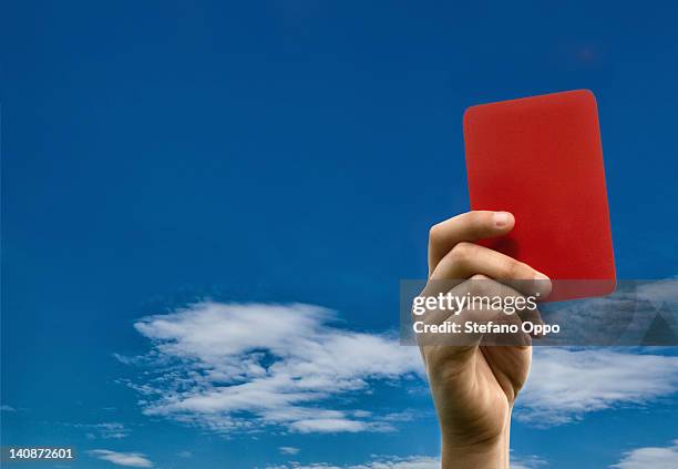 hand holding red card against blue sky - arbitro futbol fotografías e imágenes de stock