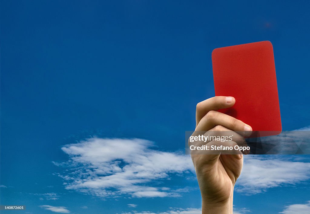 Hand holding red card against blue sky