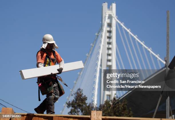 Construction worker carries material while building a section of the temporary bike path for the new Bay Bridge in San Francisco, Calif. On Thursday,...
