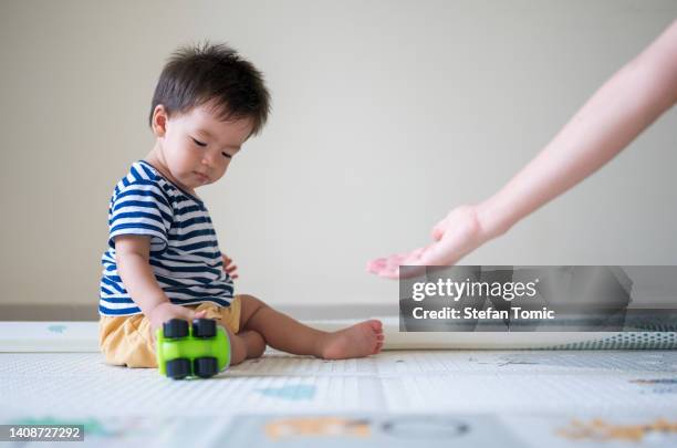 自宅の柔らかい遊びのマットの上で彼のおもちゃのトラックと遊ぶ愛らしい男の子の赤ちゃん - 敷物 マット ストックフォトと画像