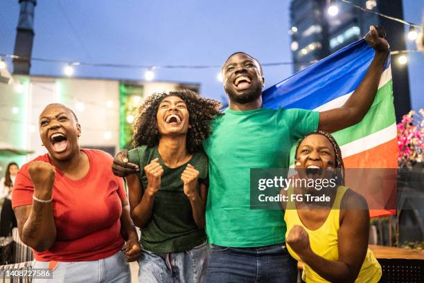 des amis célèbrent une équipe qui marque un but à l’extérieur - culture sud africaine photos et images de collection