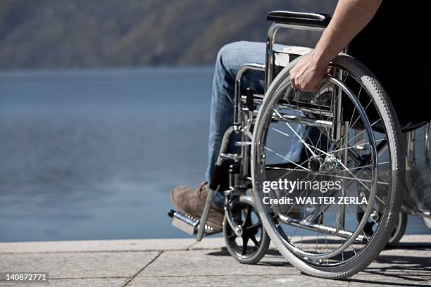 man in wheelchair sitting by water - paralysis stock pictures, royalty-free photos & images