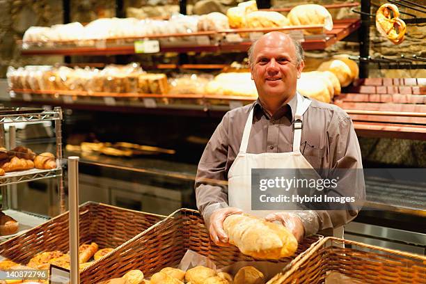 smiling baker holding loaf of bread - supermarket bread stock-fotos und bilder