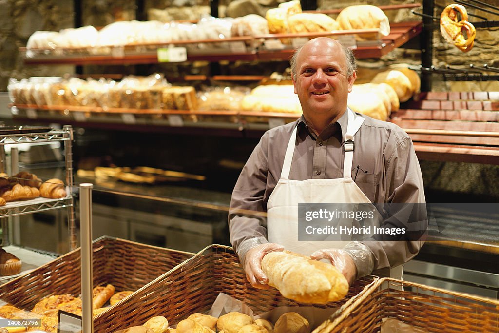 Smiling baker holding loaf of bread