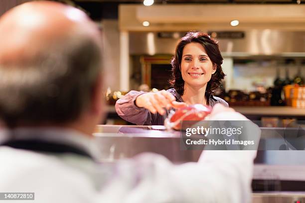 woman buying meat from butcher - carnicero fotografías e imágenes de stock
