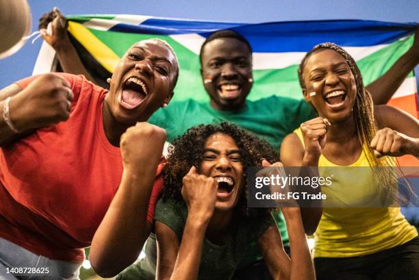 sports fan friends celebrating with south african flag outdoors - south african culture stock pictures, royalty-free photos & images