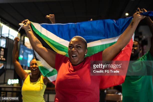 friends celebrating south african team scoring a goal in a bar - south african culture stock pictures, royalty-free photos & images