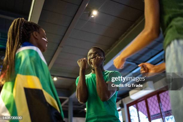 young man celebrating team scoring a goal in a bar - jamaica flag stock pictures, royalty-free photos & images