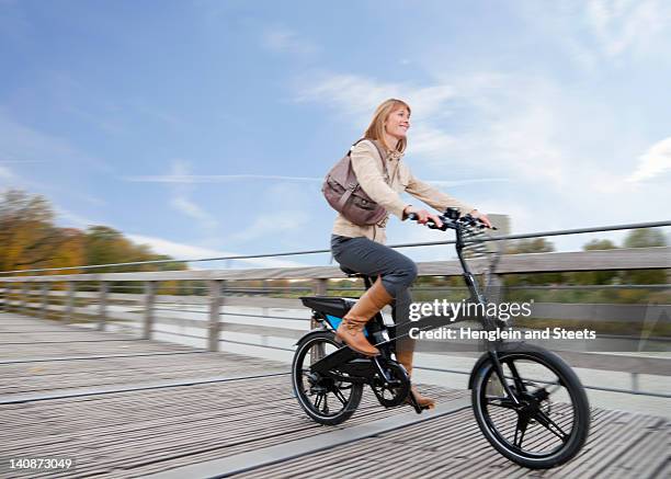 woman riding bike on wooden walkway - munich autumn stock pictures, royalty-free photos & images