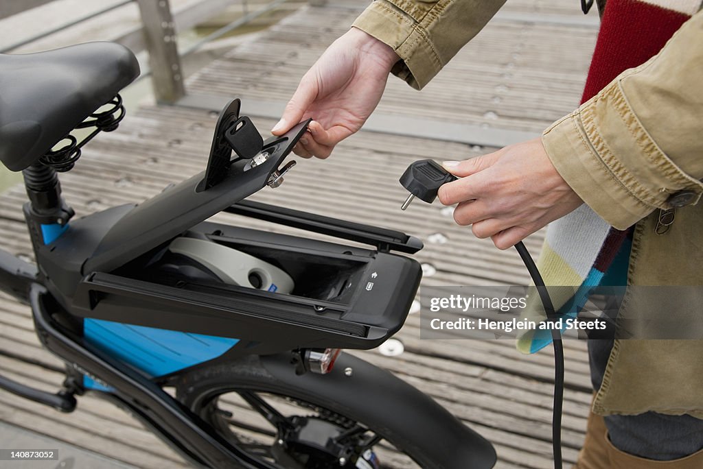 Woman charging electric bike outdoors