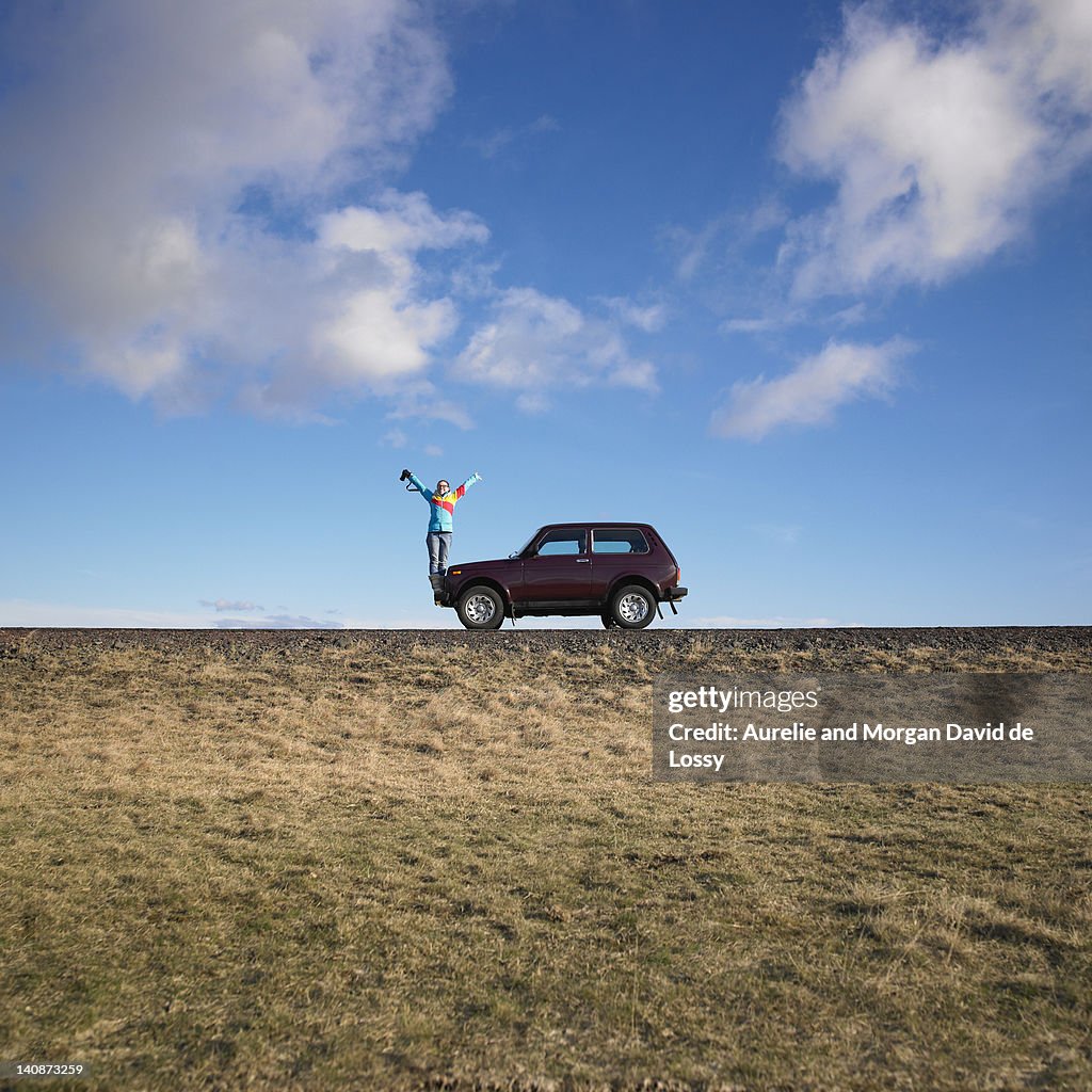 Woman standing on jeep on rural road