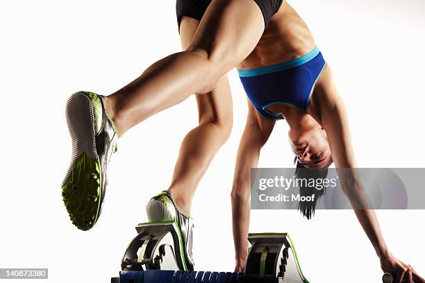 athlete putting feet into starting block - startblok atletiek stockfoto's en -beelden