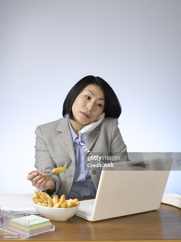 Businesswoman eating and working at desk