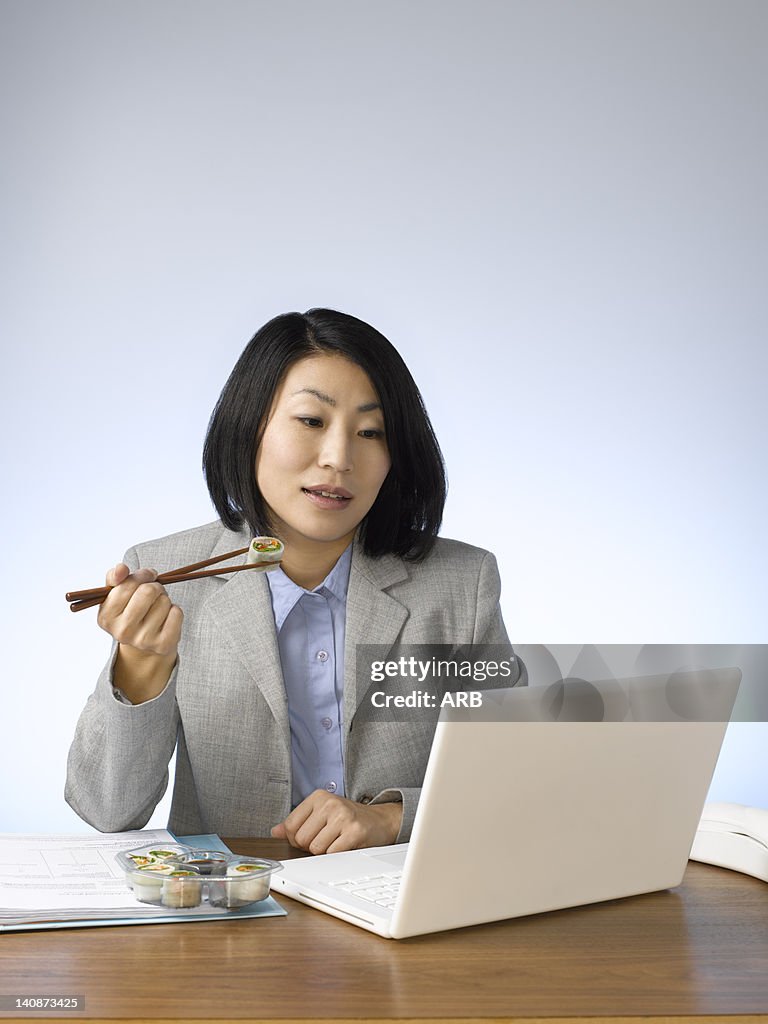 Businesswoman eating and working at desk