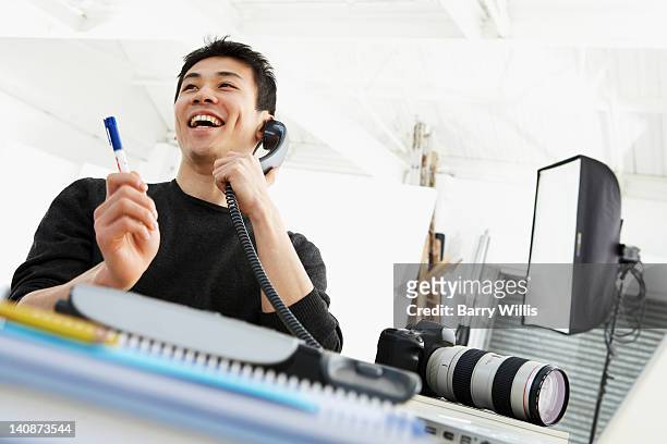 photographer talking on phone at desk - funny photographer studio stock-fotos und bilder