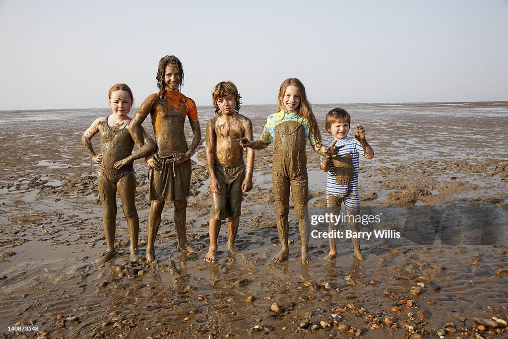 Children covered in mud on rocky beach