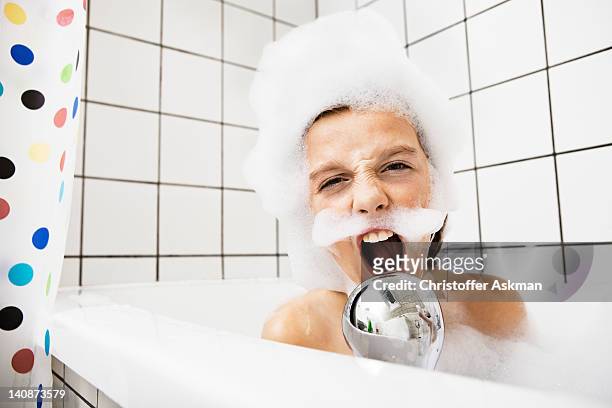 boy playing in bubble bath - zangeres stockfoto's en -beelden