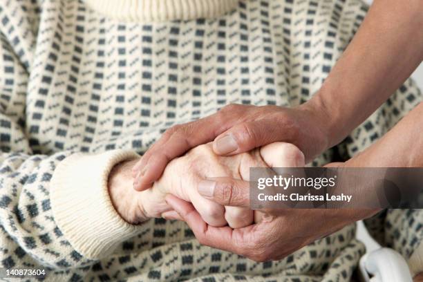 caretaker patting older mans hand - vulnerability stock pictures, royalty-free photos & images