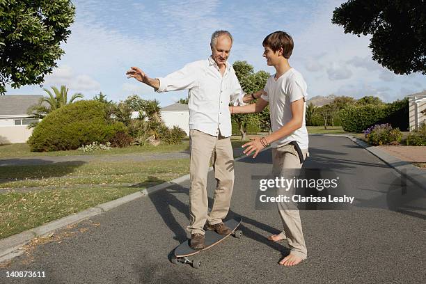 father and son playing with skateboard - teen boy barefoot stock pictures, royalty-free photos & images