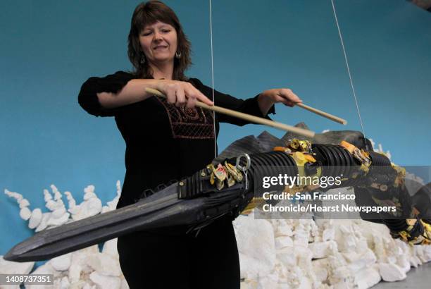 Mary Johnson drums on an eel sculpture, part of which was created with debris found from the Japan tsunami at the Washed Ashore interactive...