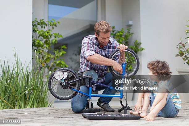 father helping son fix bicycle - bicycle repair stock pictures, royalty-free photos & images