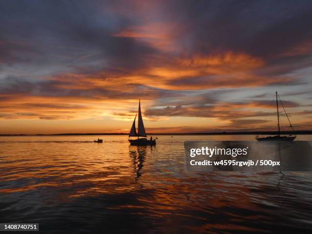 silhouette of sailboat in sea against sky during sunset - sailboat silhouette stock pictures, royalty-free photos & images