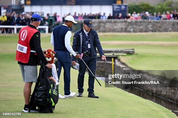 Tiger Woods of the United States speaks to rules official Mike Stewart after hitting into the water on the first hole during Day One of The 150th...