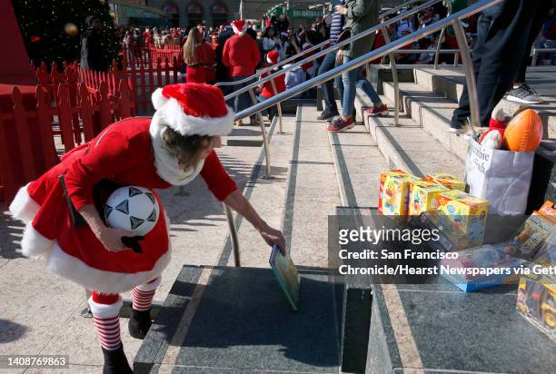 Katrina Wagner donates toys at the annual SantaCon gathering at Union Square in San Francisco, Calif. On Saturday, Dec. 8, 2018. The event was held...
