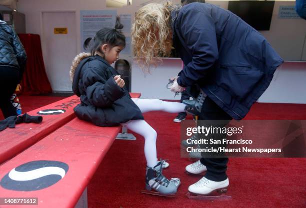 Instructor Deborah Davis laces up skates for Maja Masagca before the free skating lessons for beginners on the holiday ice rink at Union Square in...