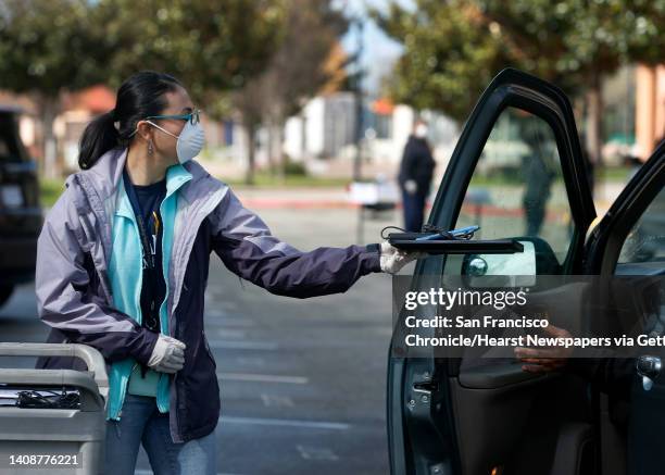 Vice principal Natalie Valencia distributes a Chromebook to parents and students driving up at Burbank Elementary School in Hayward, Calif. On...