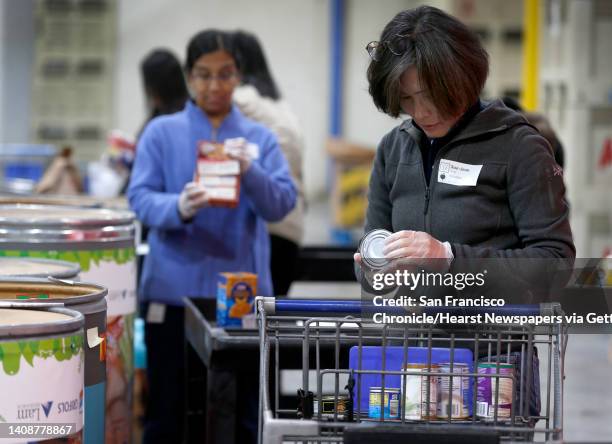 Sue-Jean Hong checks the expiration date on a can of food while volunteering at the Alameda County Community Food Bank in Oakland, Calif. On...