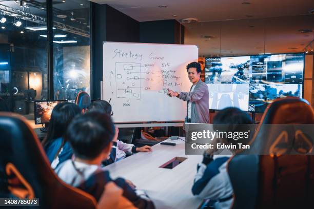 asian chinese esport team coach analysiert briefing-strategie für das team vor dem großen videospielwettbewerb im besprechungsraum mit whiteboard und fernseher - leadership in coaching stock-fotos und bilder