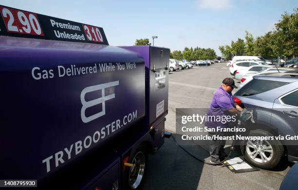 Cesar Guzman pumps gas from his Booster mobile refueling truck into a car parked in a Silicon Valley Bank parking lot in Santa Clara, Calif. On...