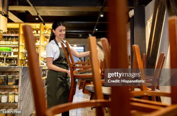 waitress closing a restaurant and putting the chairs on the tables - restaurant chairs stock pictures, royalty-free photos & images