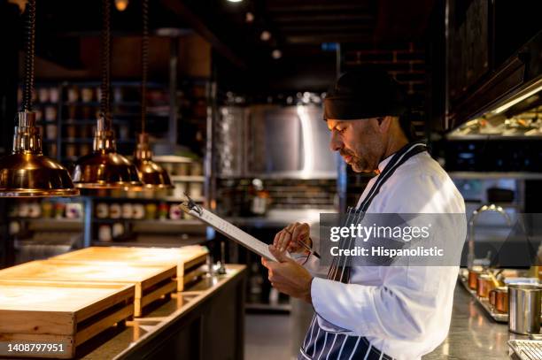 chef travaillant dans un restaurant à écrire le menu - réfléchir écrire adulte 40 ans papiers photos et images de collection