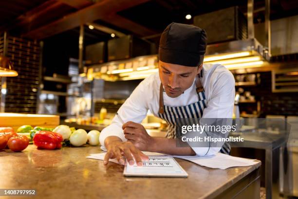 cook working at a restaurant and looking at a recipe online - menu imagens e fotografias de stock