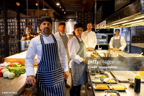 gruppe von köchen und köchen, die in der küche eines restaurants arbeiten - young chefs cooking stock-fotos und bilder